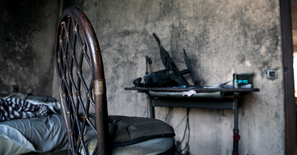 A room with some small furniture. The walls and furniture are covered in various layers of black soot.